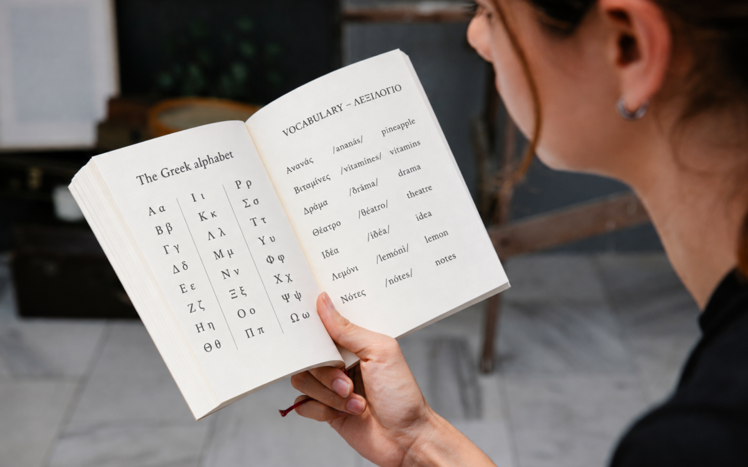 Woman reading an open book with the Greek alphabet and beginner Greek vocabulary